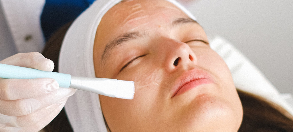 A close-up of a facial treatment, with a professional applying a product to a woman's face.